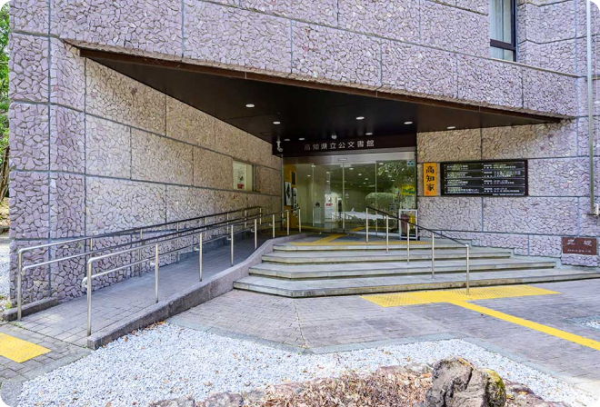 写真:高知県公文書館の建物入り口。階段の隣に手すり付きのスロープがあります。入り口は自動ドアです。