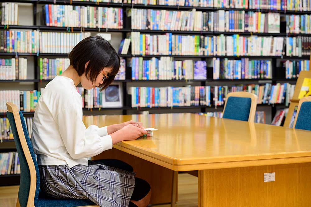 写真:机で本を読んでいる女の子