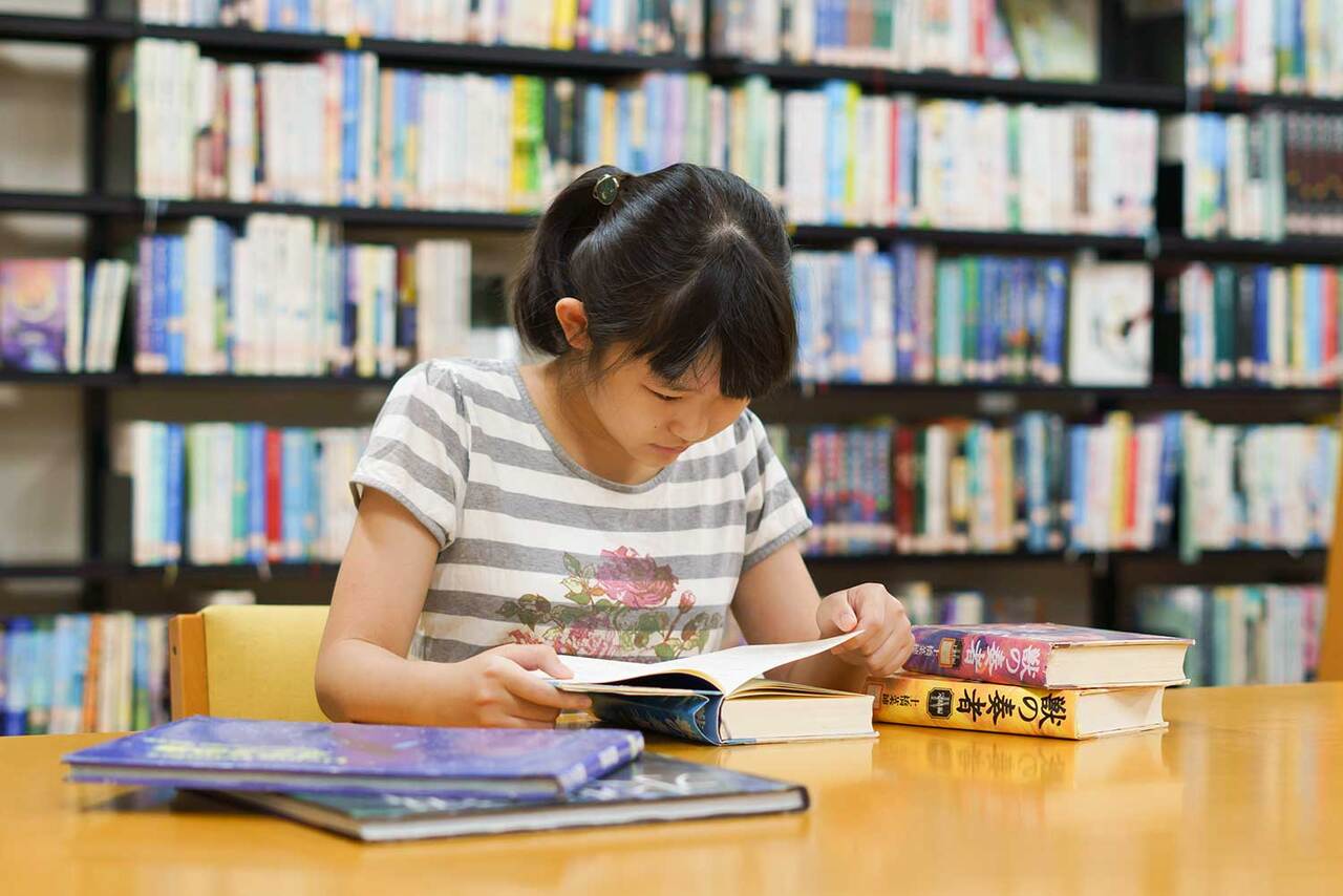 写真:女の子が閲覧テーブルで本を読んでいます