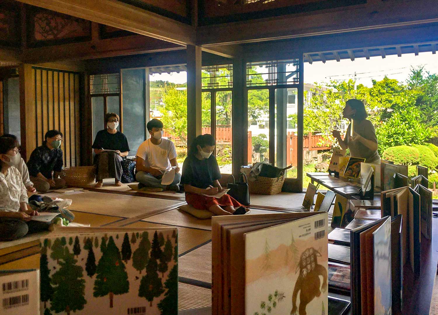 写真：本をたくさん並べて、大人の人にお話をしています
