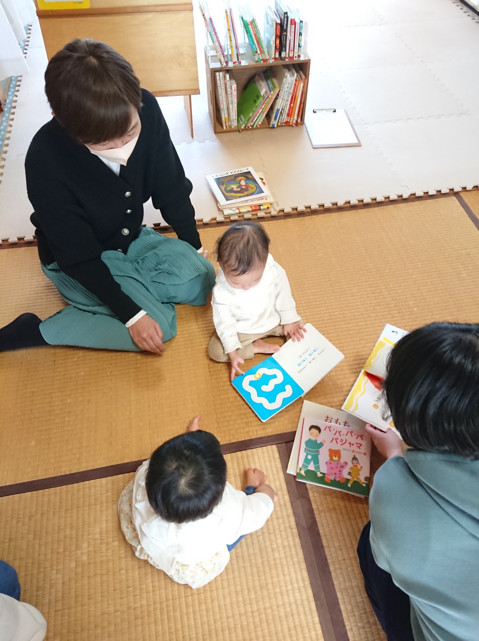 写真：赤ちゃんが絵本を広げて見ています。