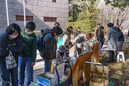 写真：館外の広場で、バザーにきたお客様が購入する本を選んでいます。