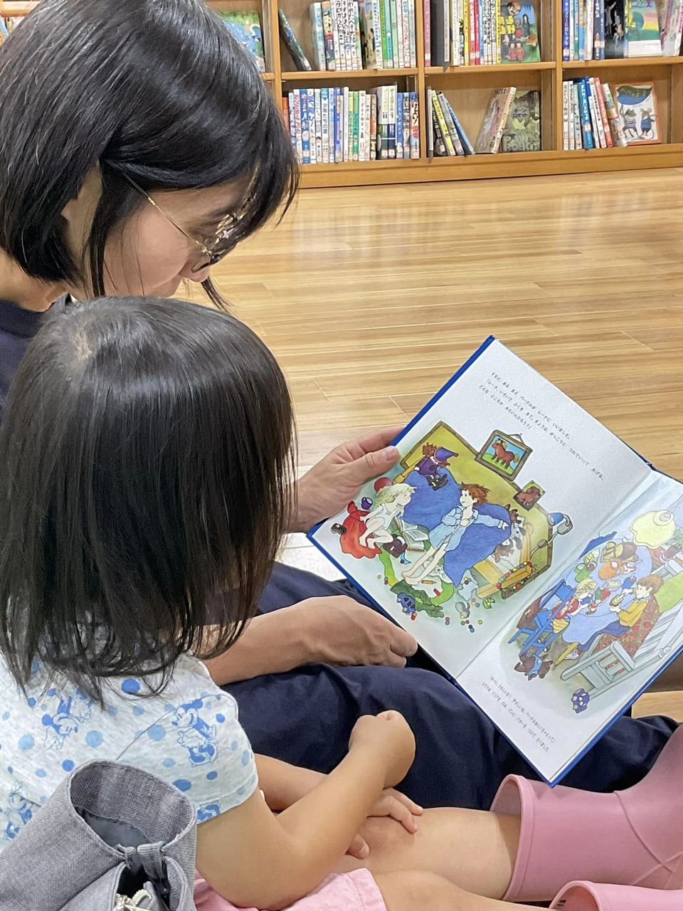 写真：お母さんとこどもが絵本を読んでいます。