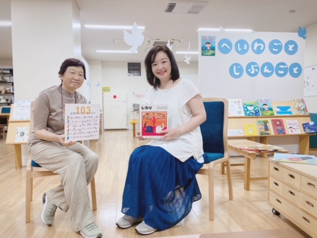 写真：職員の大木と理事の深瀬が本を手に椅子に座っています。