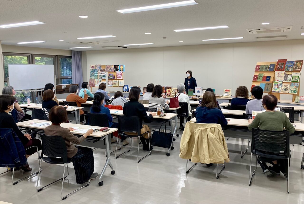 写真：講義のようす　アリスの本を前に話す安田先生