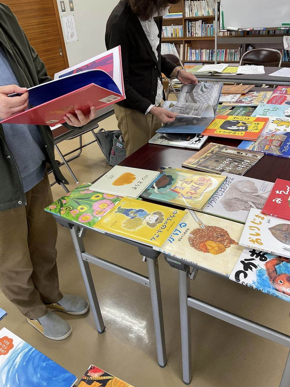 写真：参加者が読み聞かせにおすすめの絵本を手にとっています。