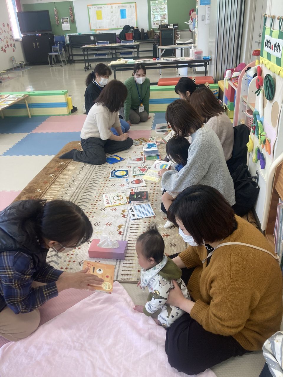 写真：赤ちゃんに絵本を見せています。