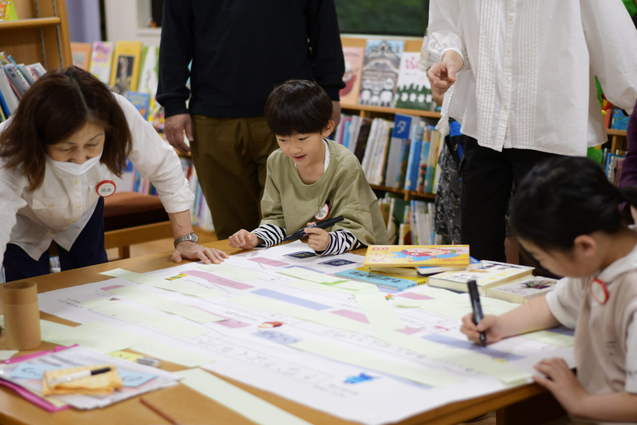 写真：ペンを持って模造紙を見つめる男の子です
