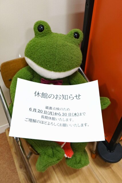 カエルのぬいぐるみがご案内の紙を持っている画像