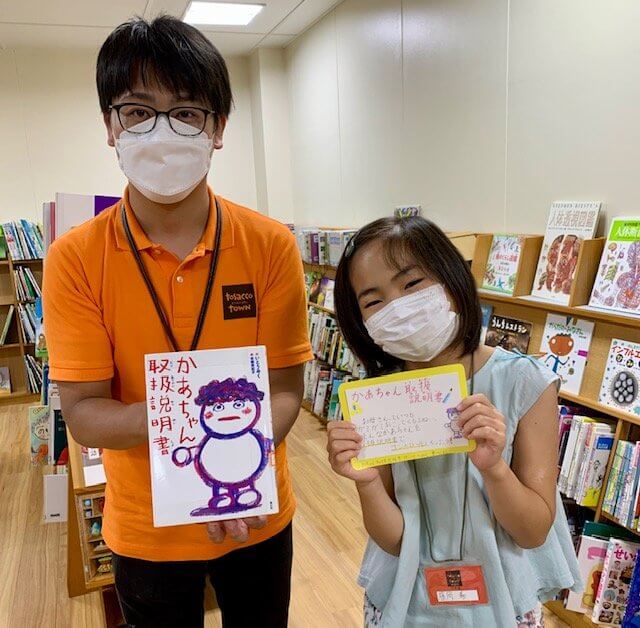 写真：小学生が本の自作のポップを持っています。