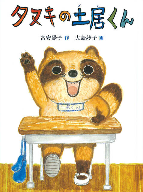 画像：たぬきのこどもが机に座って手をあげています。