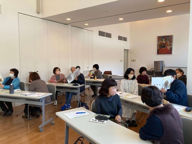 写真：講座参加者の皆さんがペアで絵本を読み合っています。