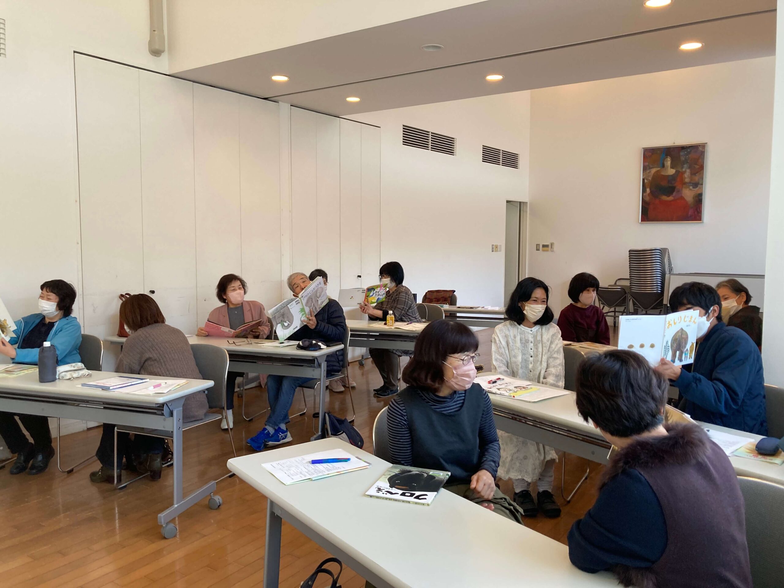 写真：講座参加者の皆さんがペアで絵本を読み合っています。