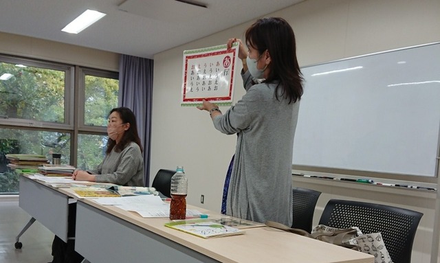 写真：講師の花房さんがカードを手に説明しています。