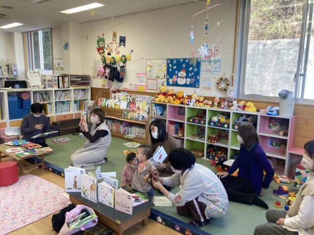 写真：乳児づれのお母さんが本を読んでいます。