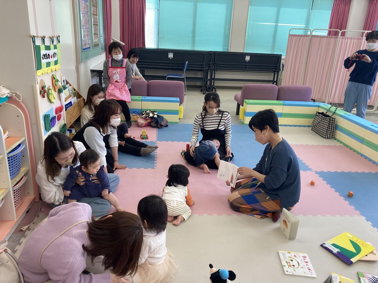 写真：赤ちゃんと保護者に絵本を読んでいます。