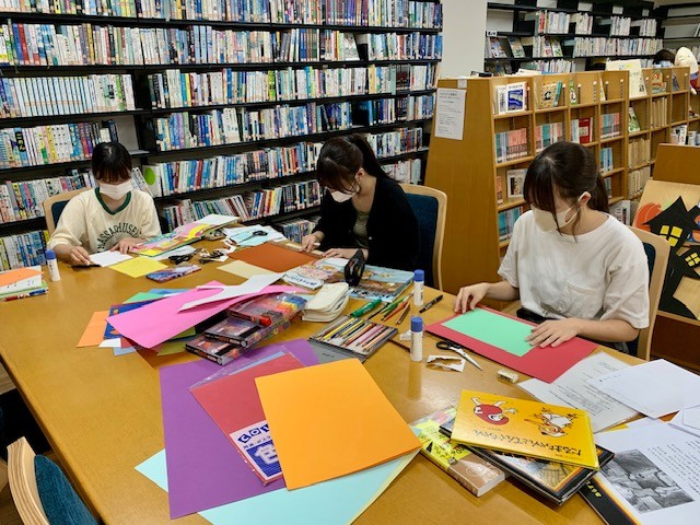写真：大学生がポップ作りをしています。