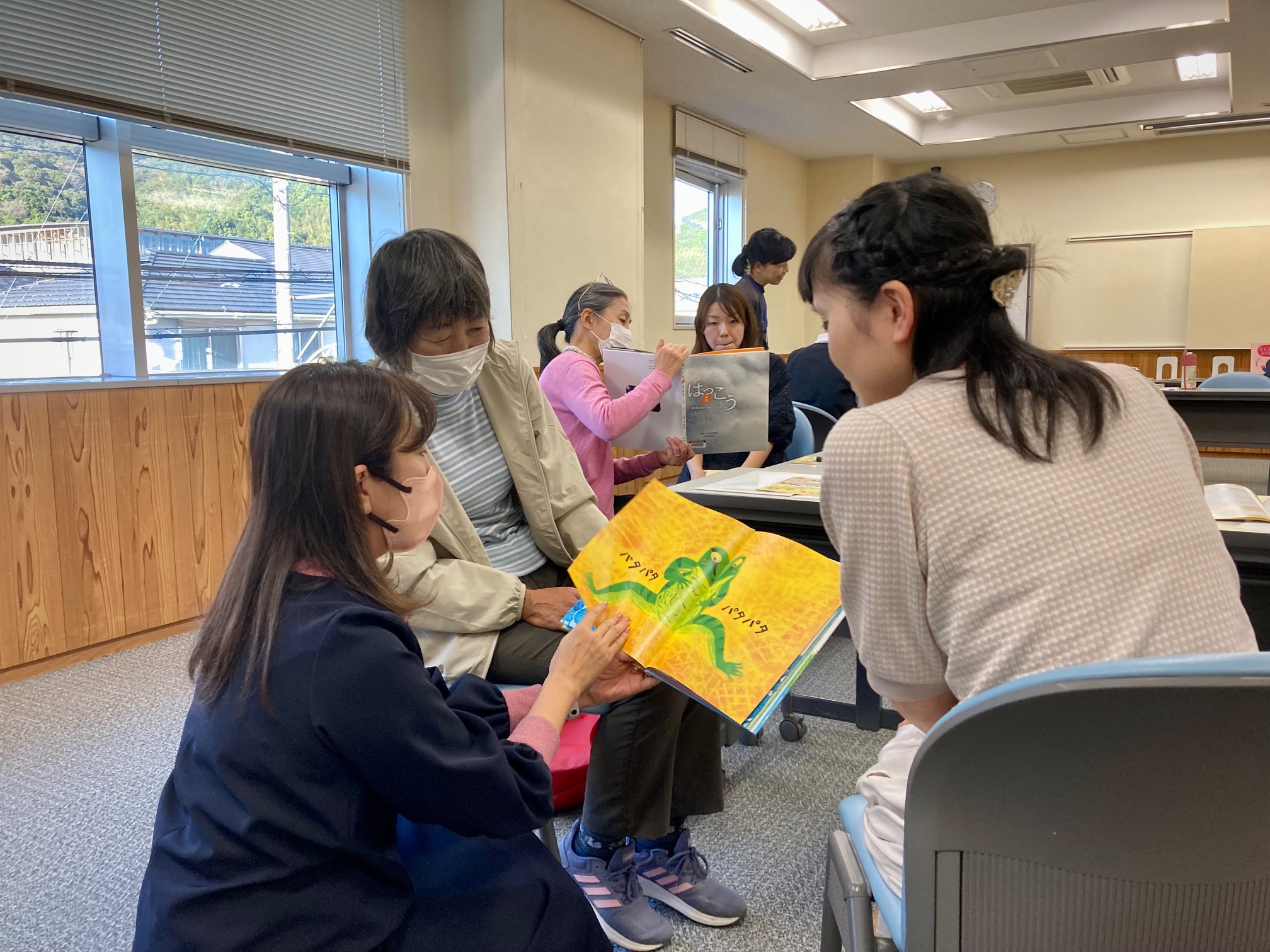 写真：講師の花房が参加者と絵本を読み合っています。