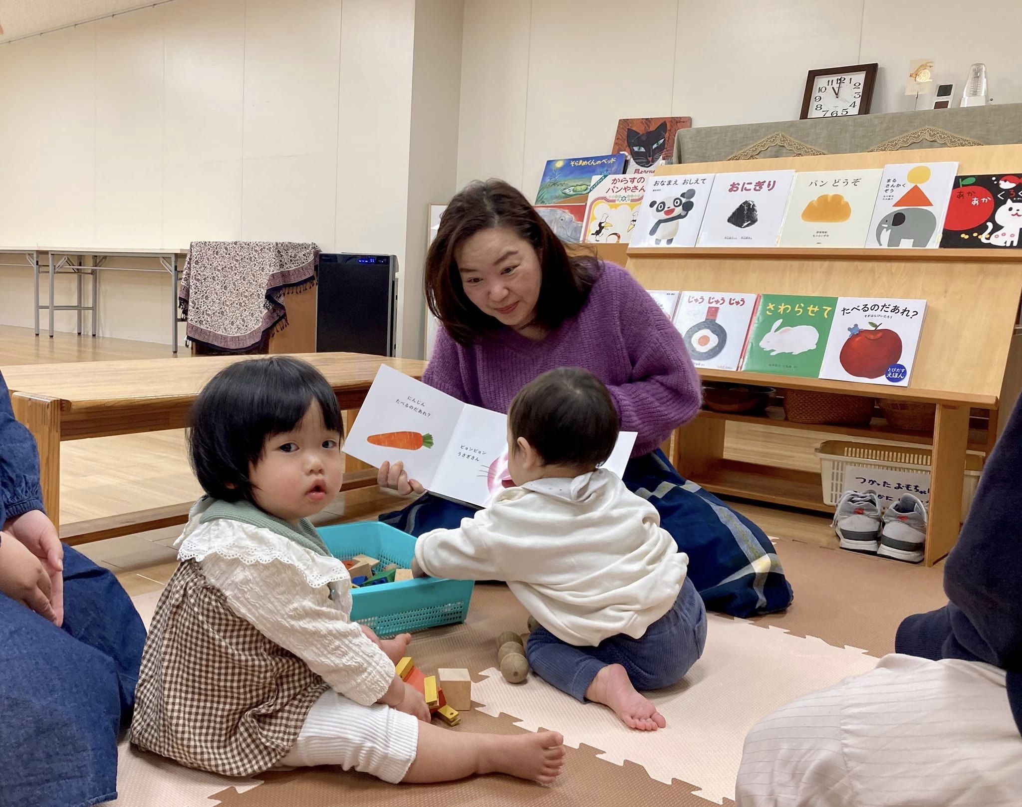 写真：大木が小さなお子さんに絵本を読んでいます。