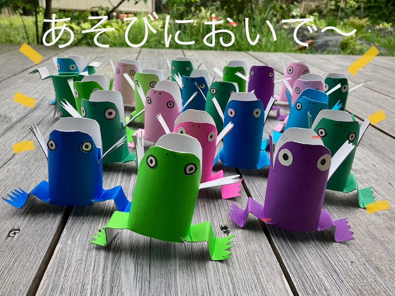 写真：折り紙のカエルがたくさん並んでいます。キャプション：あそびにおいでー